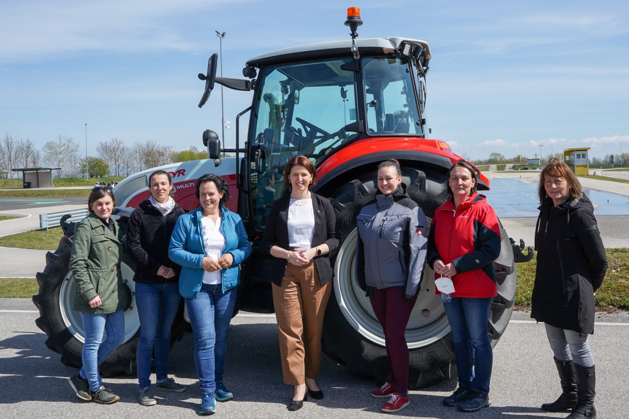 Women students stand in from of a tractor
