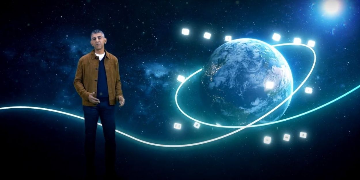 Sumit Dhawan standing in front of backdrop depicting space and planet Earth