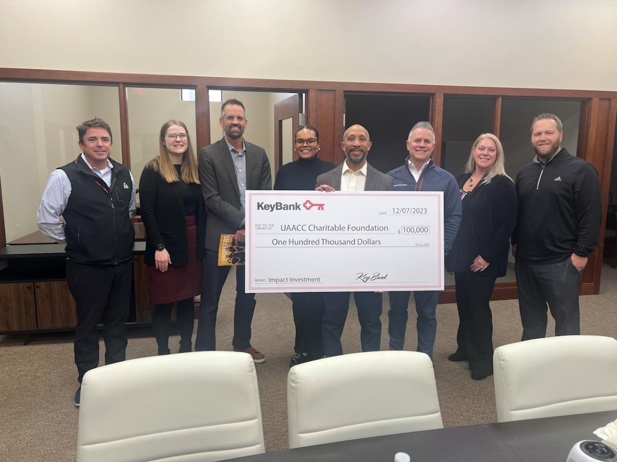 KeyBank and UAACC representatives shown holding a grant check for $100,000.