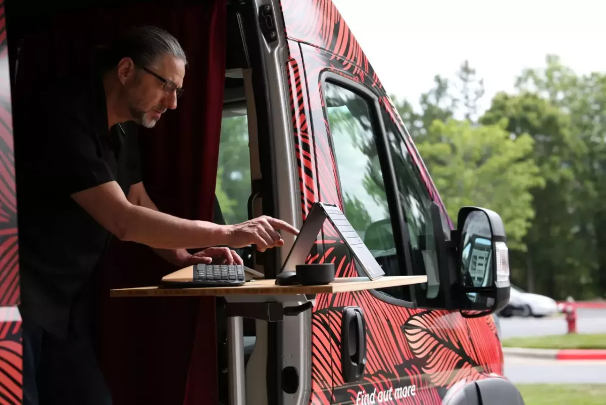 A person working on a laptop out of the side of a van.