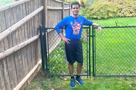 Vinamra Shukla in running gear standing on a green lawn in front of a gate