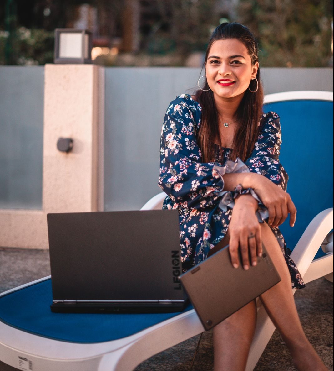 Vishakha Fulsunge in a dress sitting next to a Lenovo laptop and holding a tablet