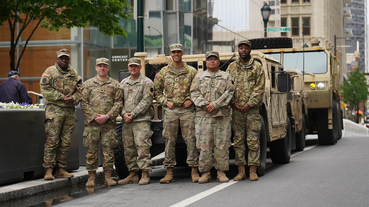A group of members of the armed forces in front of an armored truck.