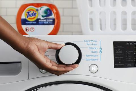 Person turning the dial on a washing machine 