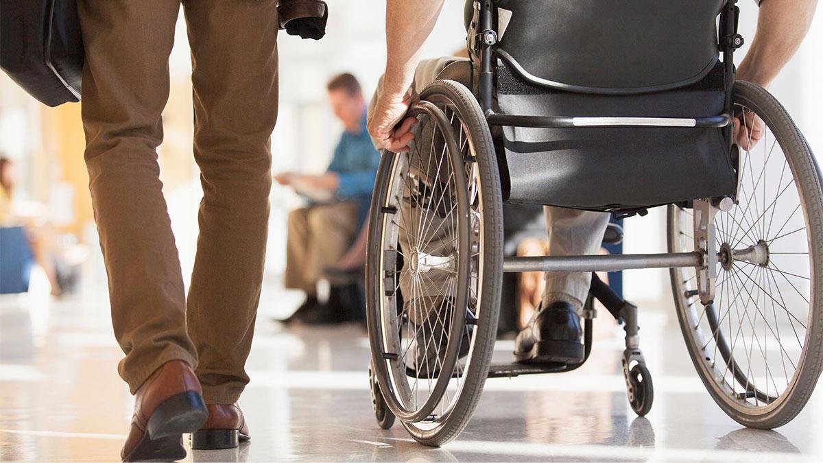 A person sitting next to a person in a wheelchair 