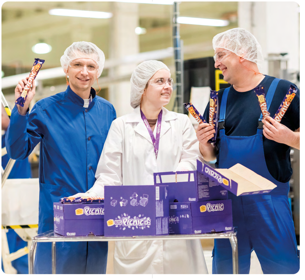 Three workers in their uniforms holding Mondelēz products