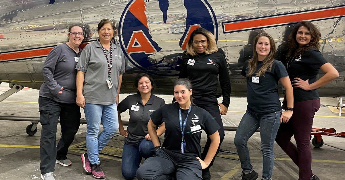 7 women standing with a plane