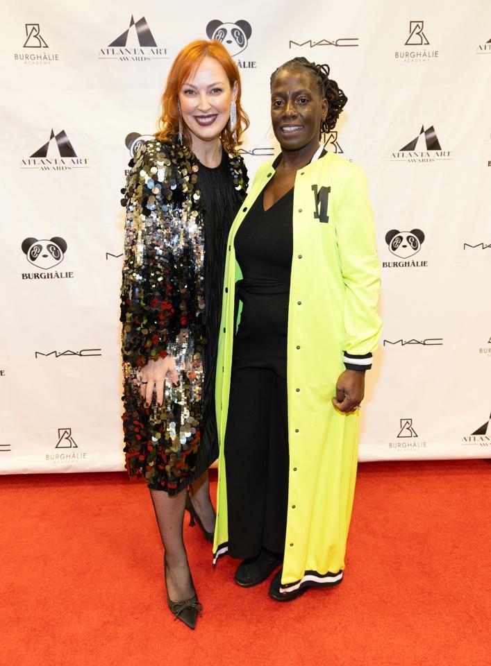 Two smiling people on a red carpet at the gala.