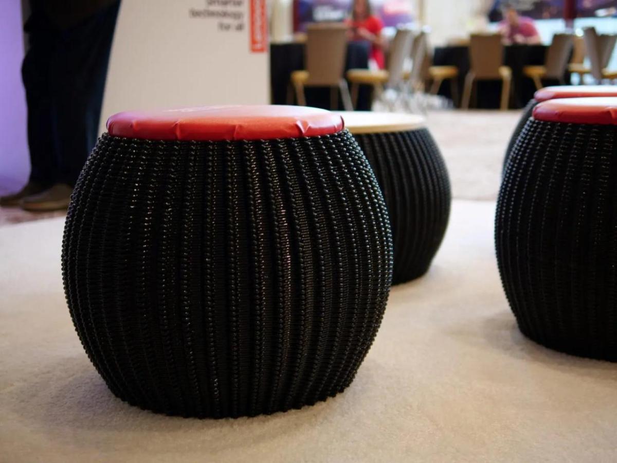 Multiple black stools made by the 3D printer on display.