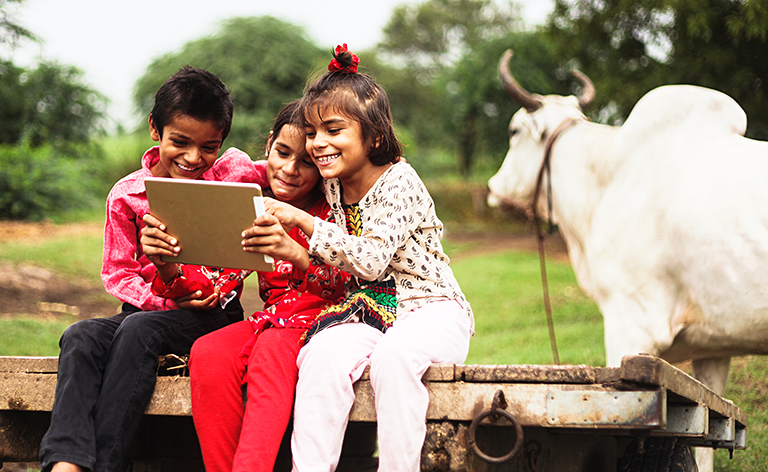 3 kids using a tablet in front of a bull
