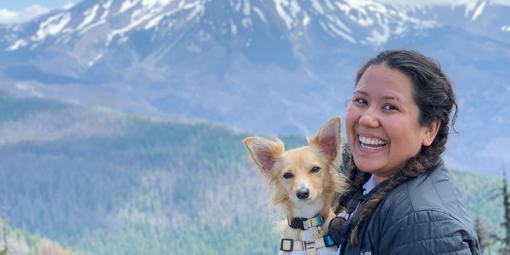person and dog in front of mountain landscape