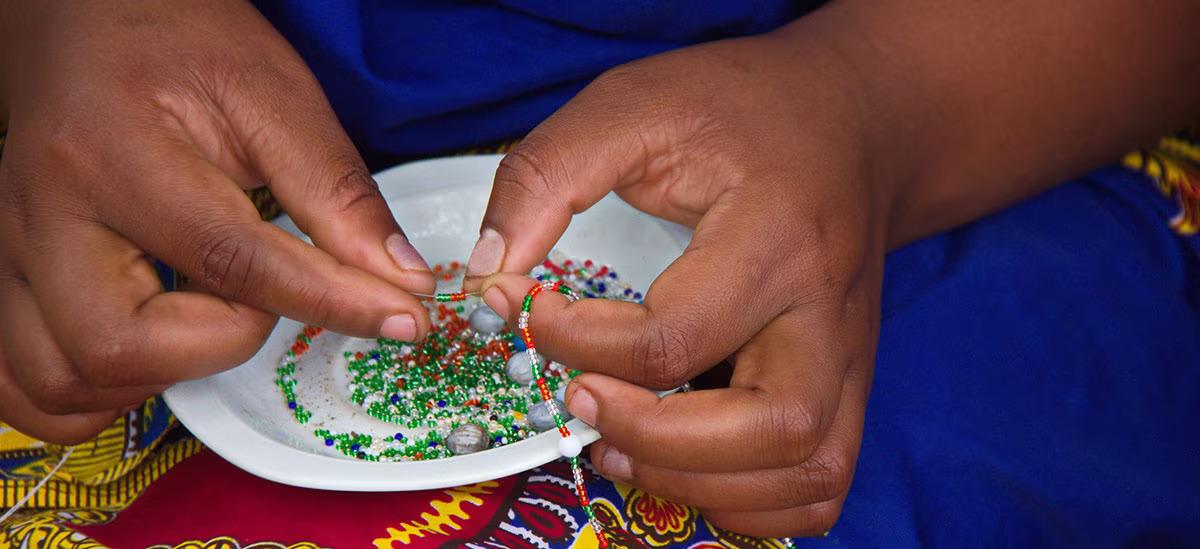 Close up of a person stringing beads.