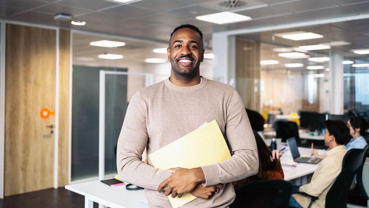 Black adult male at work holding folder of Black History Month information