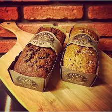two loaves of packaged bread on a wooden board in front of a brick wall
