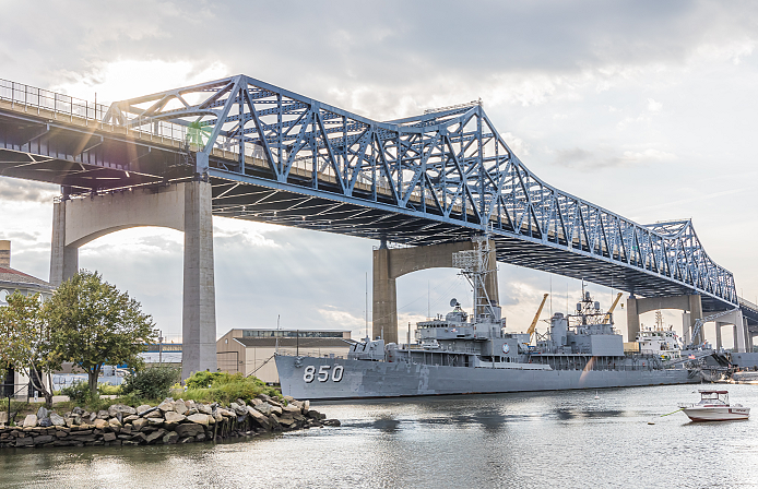 a large bridge over a water way and boat underneath