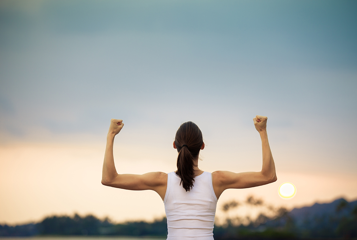 Person flexing muscles at sunrise