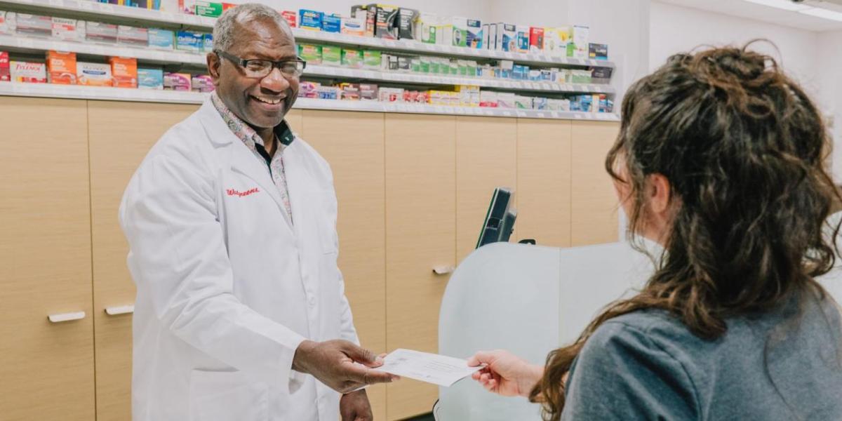 Calvin Bryant, pharmacist, handing something to a customer.