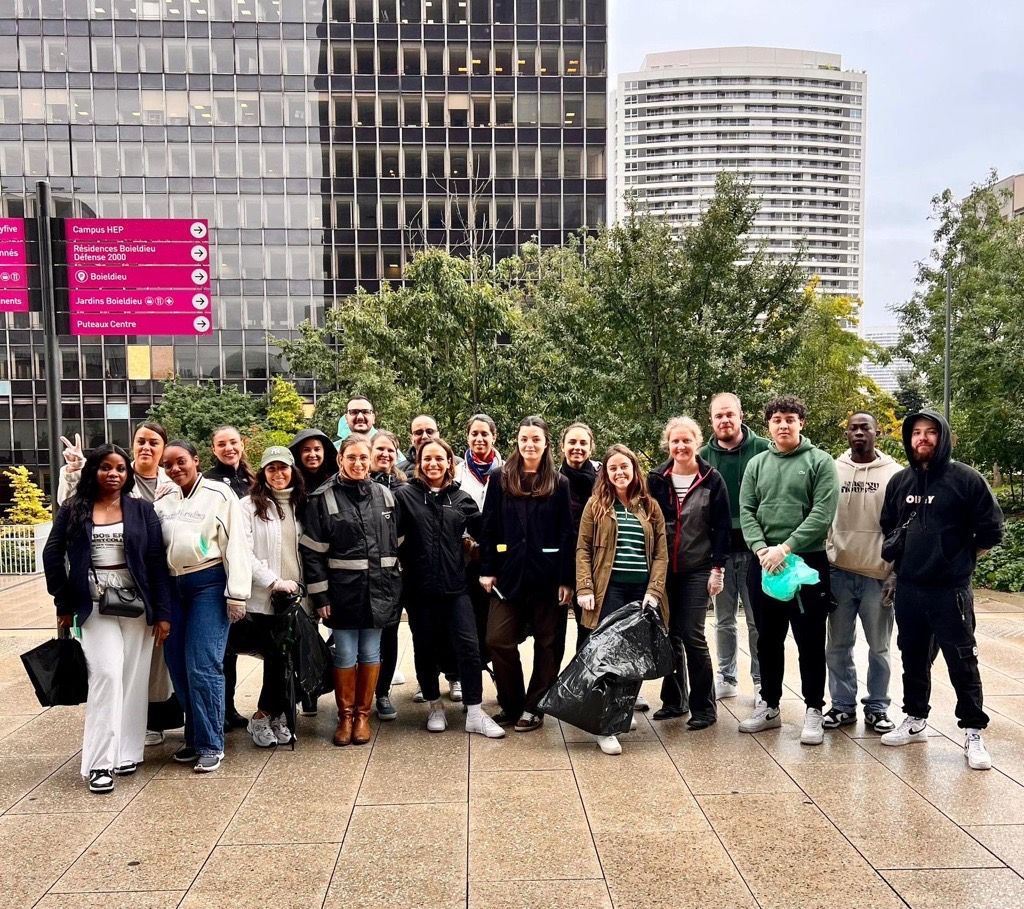 A group posed together outside. Some holding black trash bags.