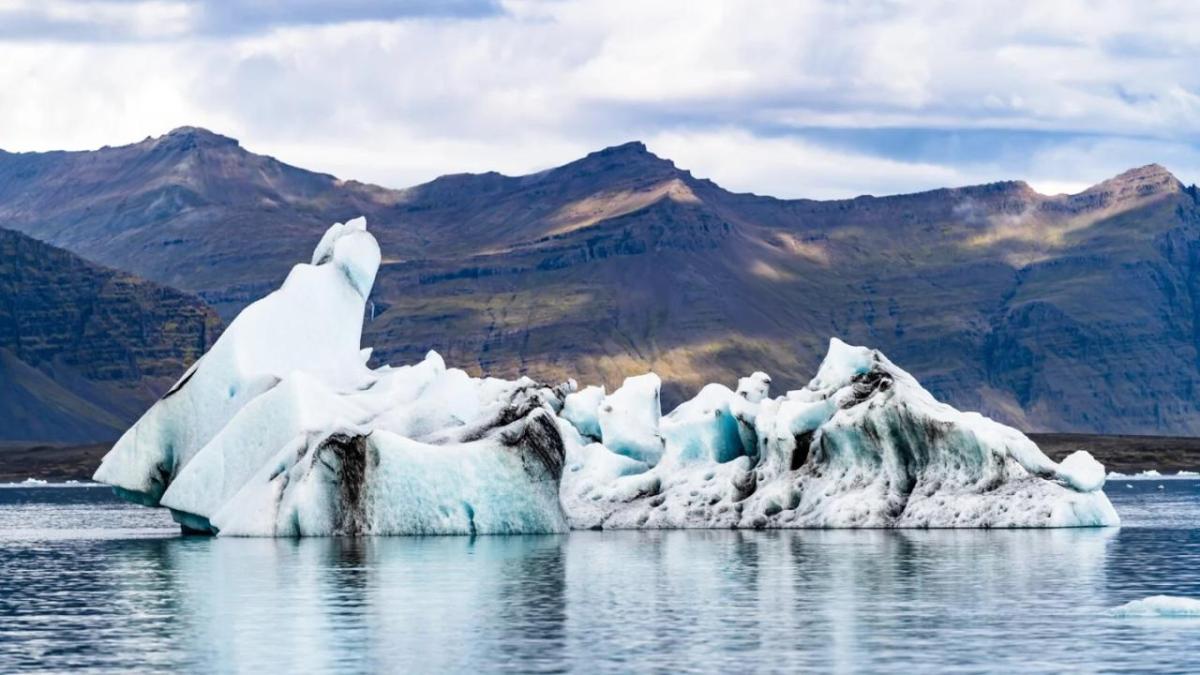 muddy iceberg with mountains in the background