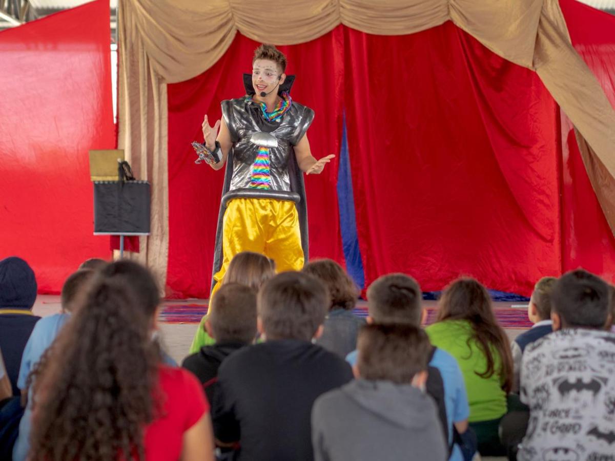 A person in costume performing for an audience of children.