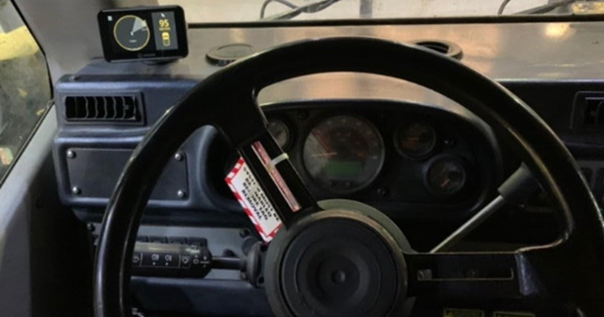 Inside of a heavy machinery vehicle, a warning label and monitor on the dashboard.