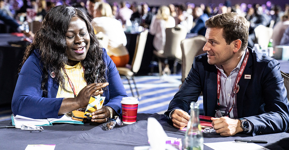 Two people talking at a table at the conference