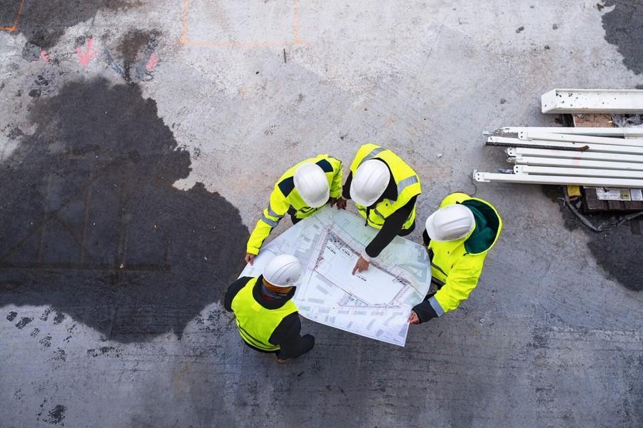 Aerial view of four construction workers overlooking a blueprint.