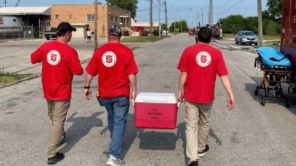 Three volunteers walking away, two carrying a cooler.