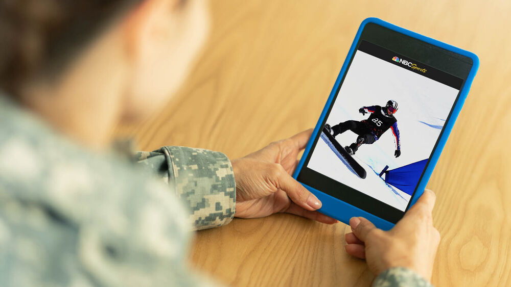 Service member watches a snowboarder on a handheld device