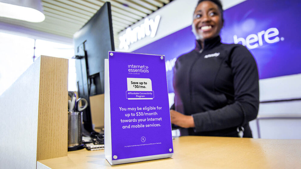Xfinity Employee stands behind a cash wrap smiling