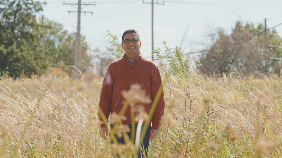 A smiling person standing in a field of cover-crop