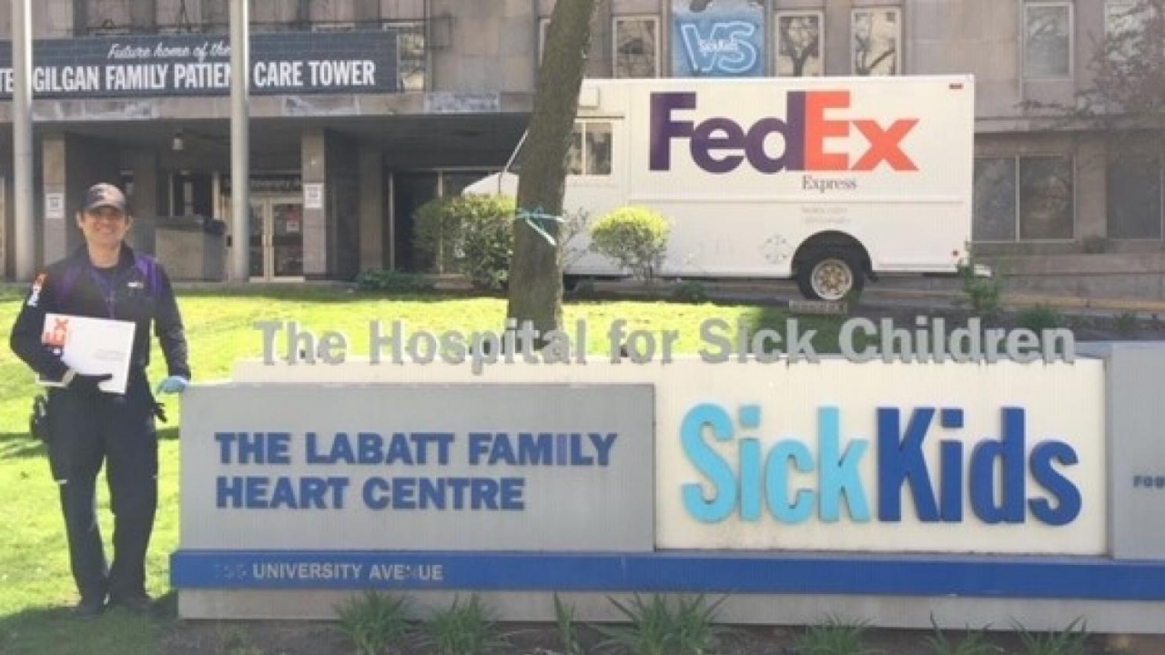 FedEx Employee standing next to Sick Kids sign