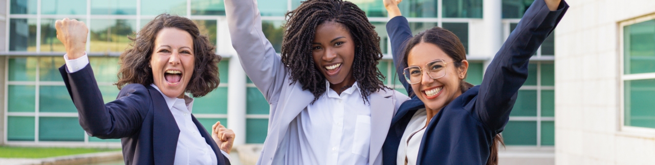 3 women celebrating in front of a building