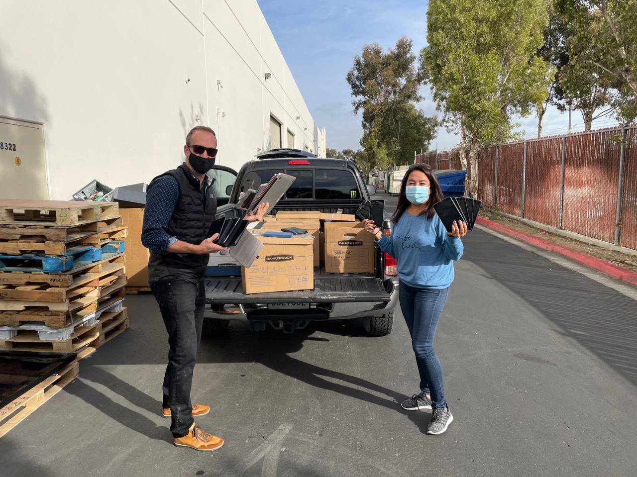 Jeff Monday (L), Qualcomm Vice President of Sales, helps Vida Roozen (R) of Creative Channel Services unload over 300 computers, tablets, headphones, monitors, and printers that Creative Channel Services, graciously donated.