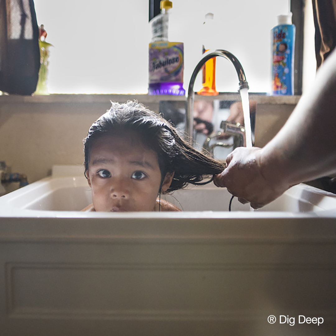 Child getting hair washed in sink