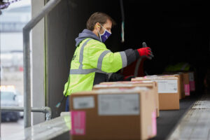 Masked FedEx Employee scanning a package