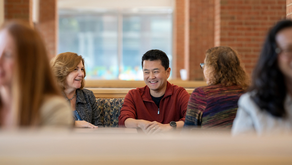 3 employees sitting, talking and laughing.