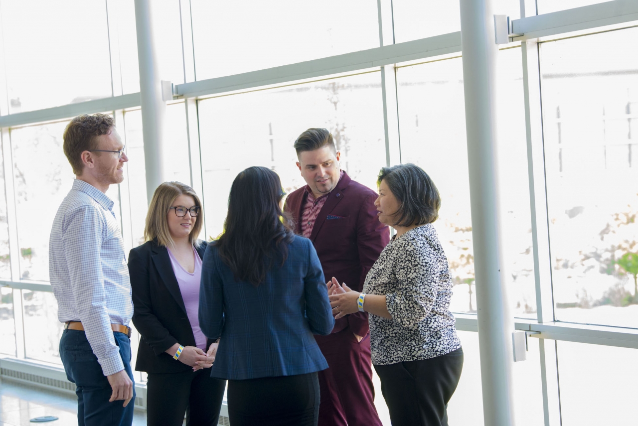 Five employees standing in a group talking