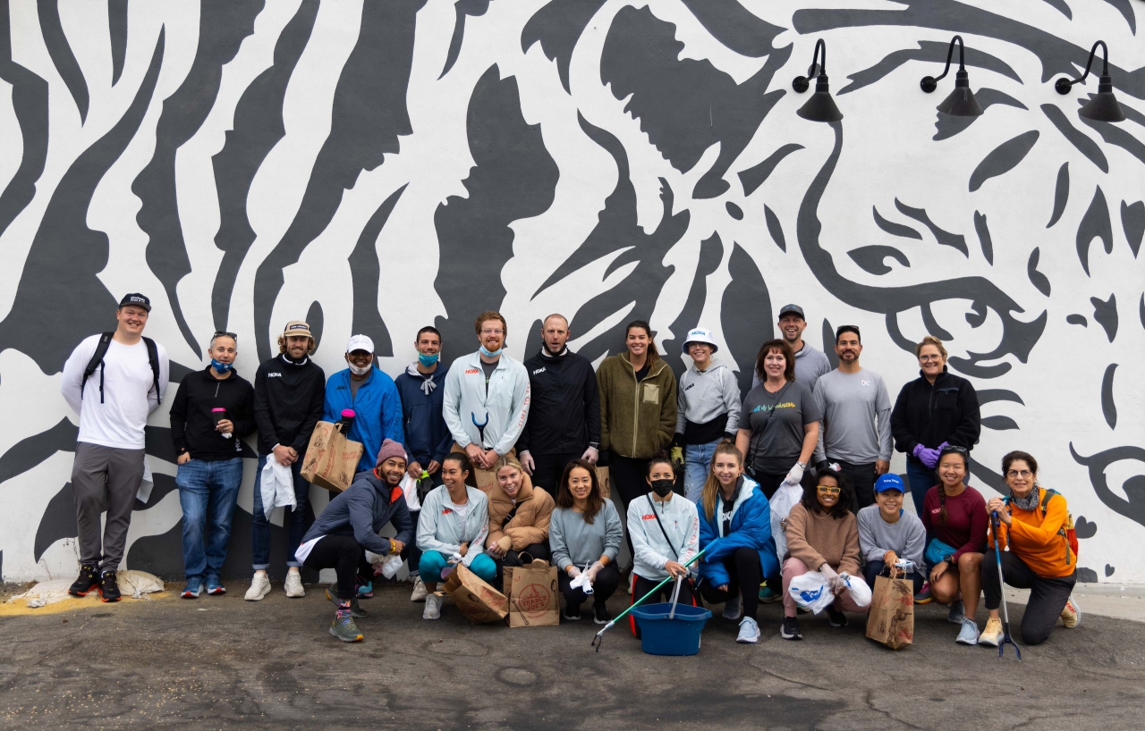 A group of volunteers stand in front of a mural of a black and white tiger