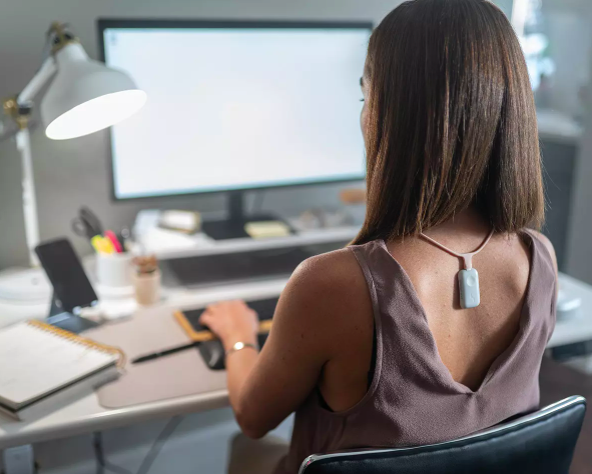 Woman sitting at desk wears device that helps avoid slumping in chair