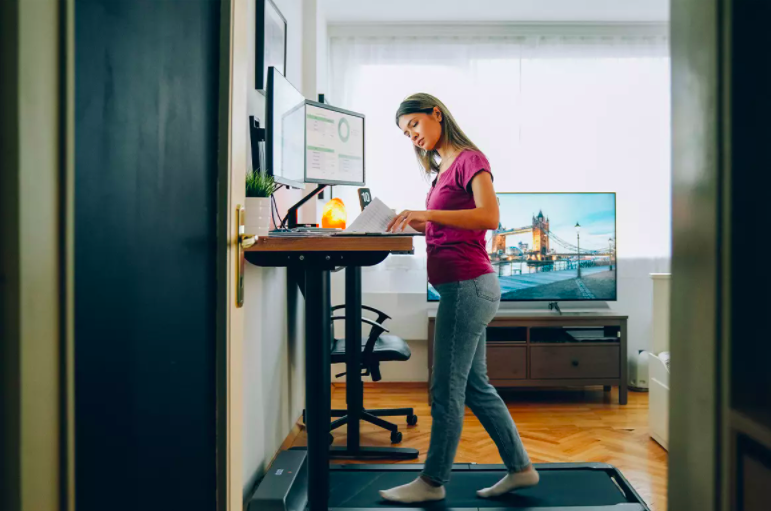 Woman at standing desk with walking treadmill underneath 