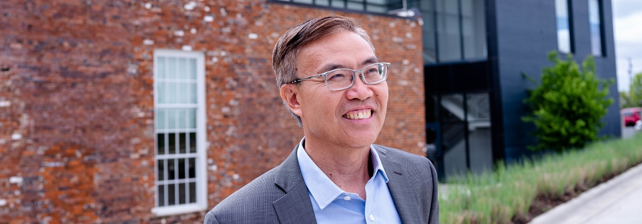 Ben Zhang outside, a brick building in the background