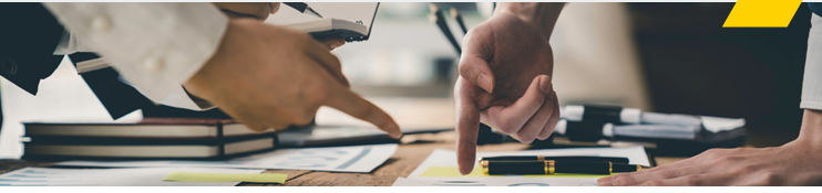 Two people pointing to a piece of paper.