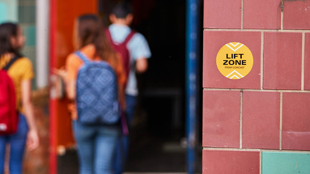 Kids walk into school marked with sticker that reads: Lift Zone From Comcast
