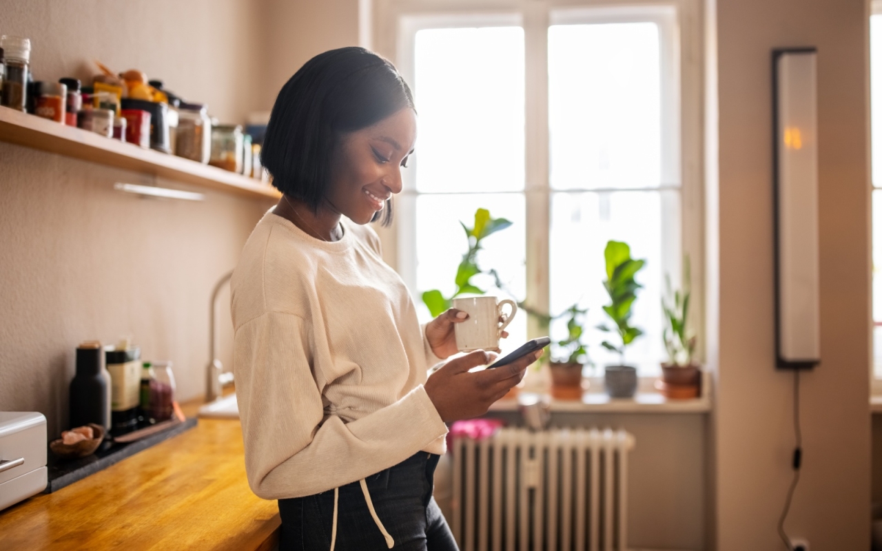 Person using phone and holding a mug