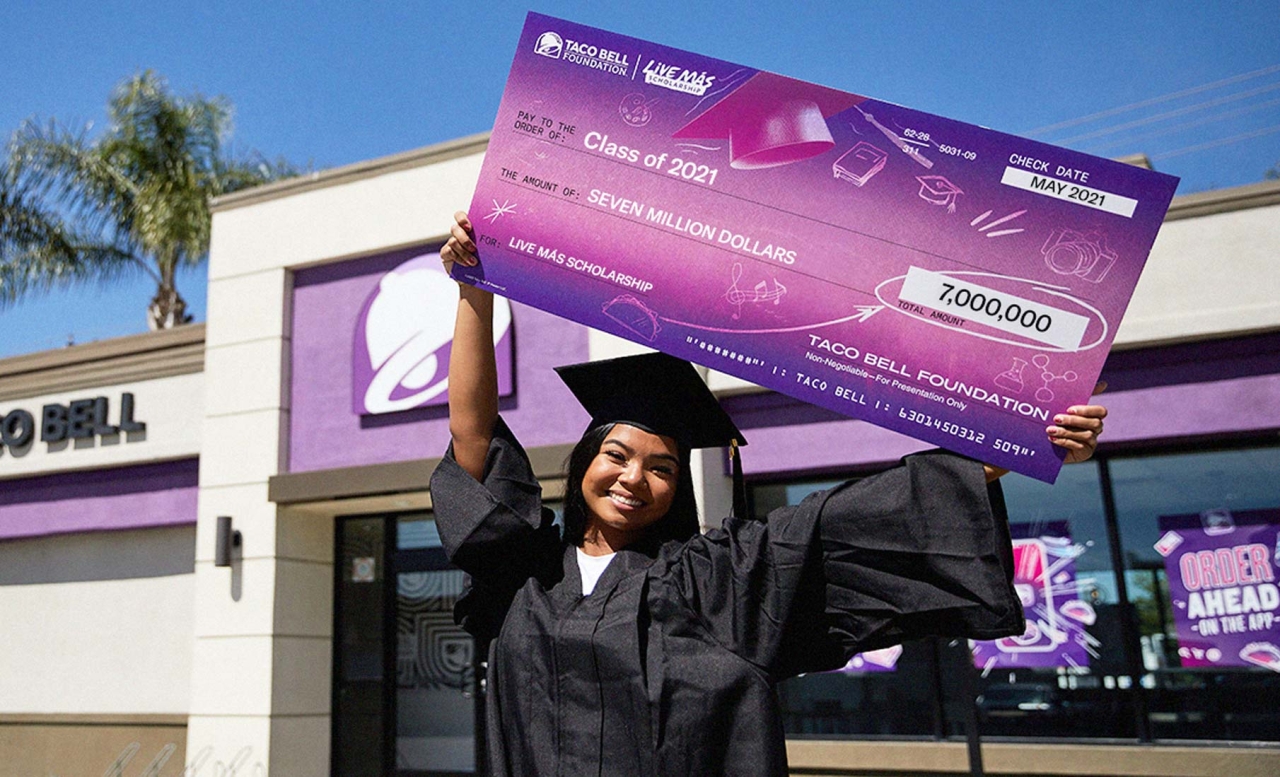 Graduate poses with big taco bell check