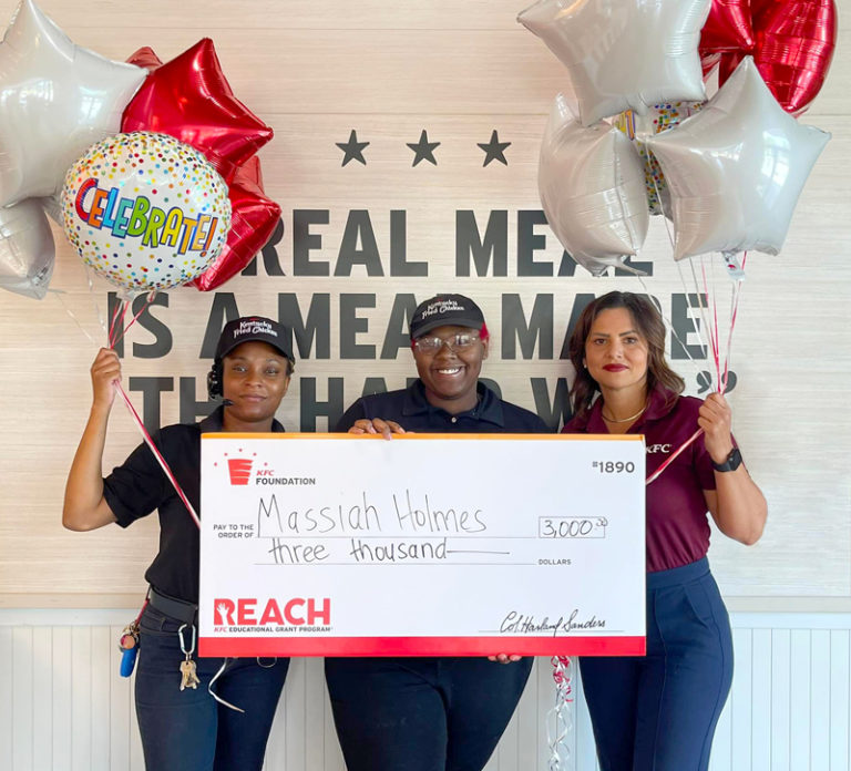 3 people hold a big check and balloons together 