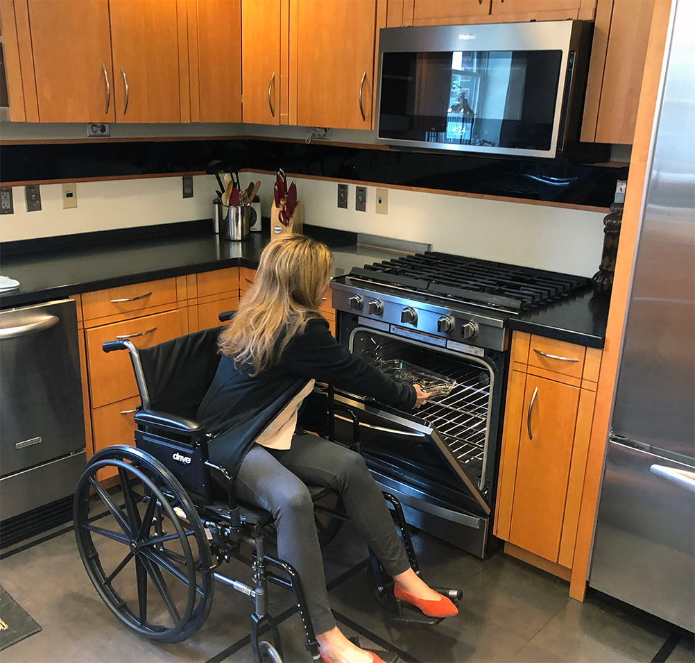 woman in a wheelchair places a glass casserole dish in an oven