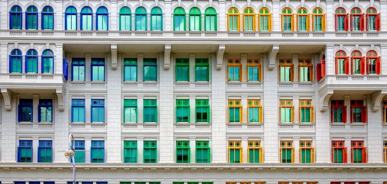 exterior view of rows of rainbow colored window frames on a white building