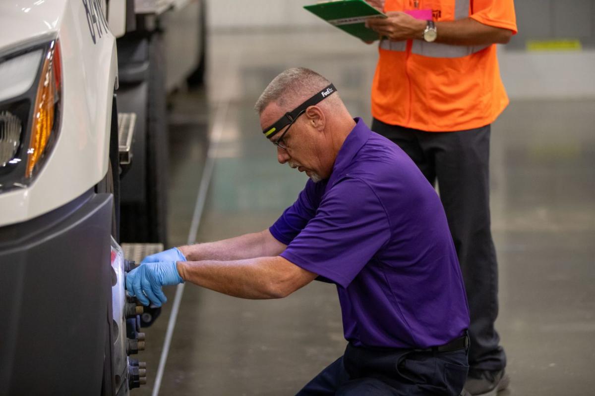 fedex driver working on a wheel of a truck